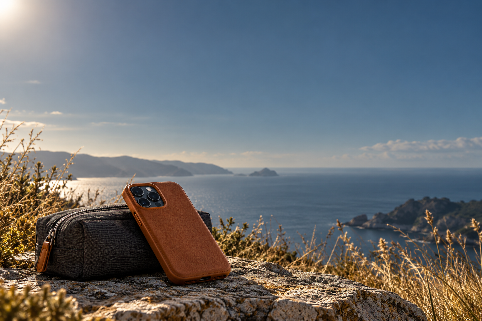 Étui de téléphone en cuir et pochette devant un paysage côtier